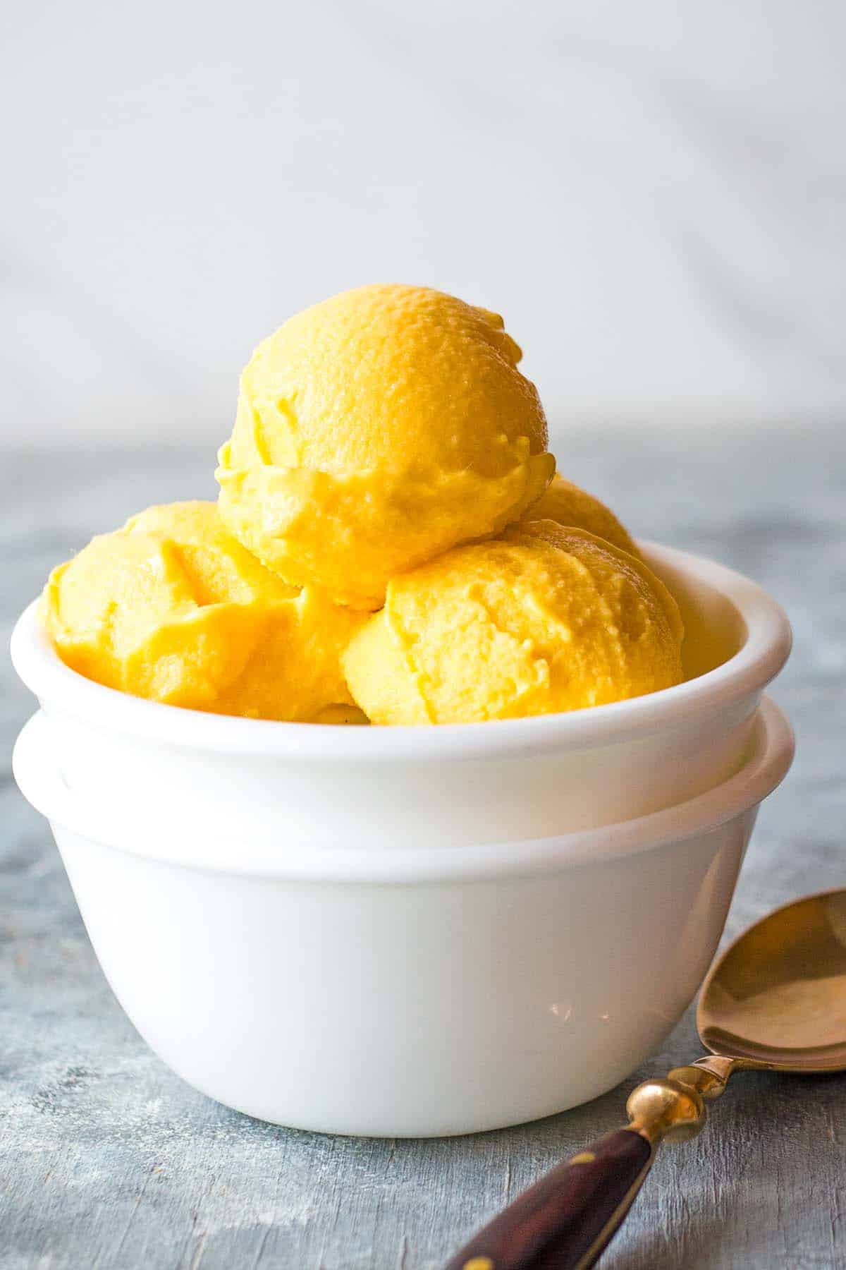scoops of frozen yogurt with mango in small white bowls