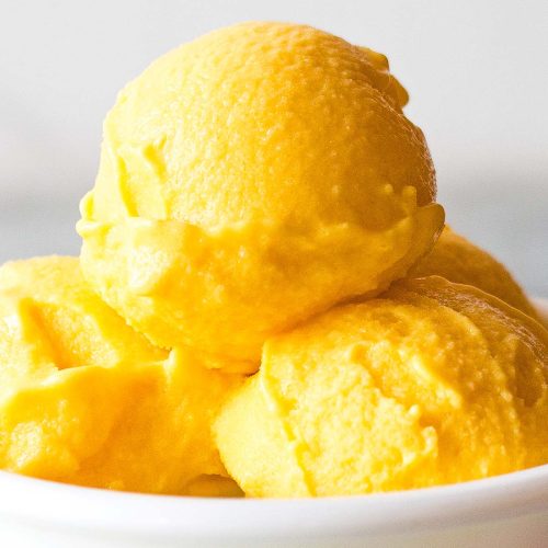 close up of mango frozen yogurt scoops in small white bowl
