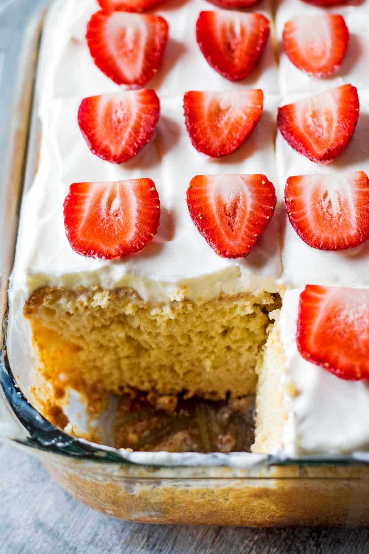 tres leches cake in cake pan with slice removed to reveal fluffy inside cake texture