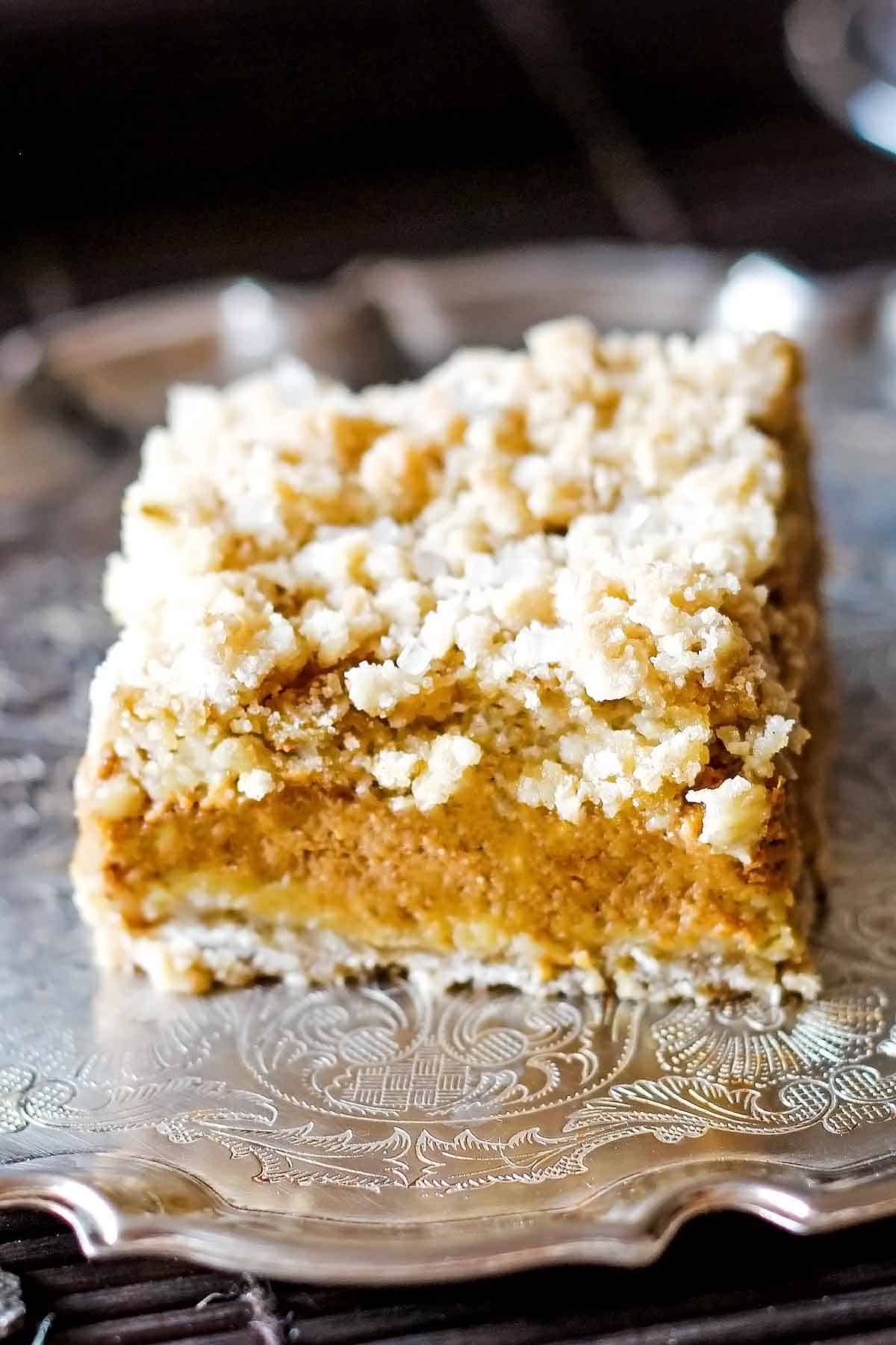pumpkin bar with crust and crumb topping on silver platter