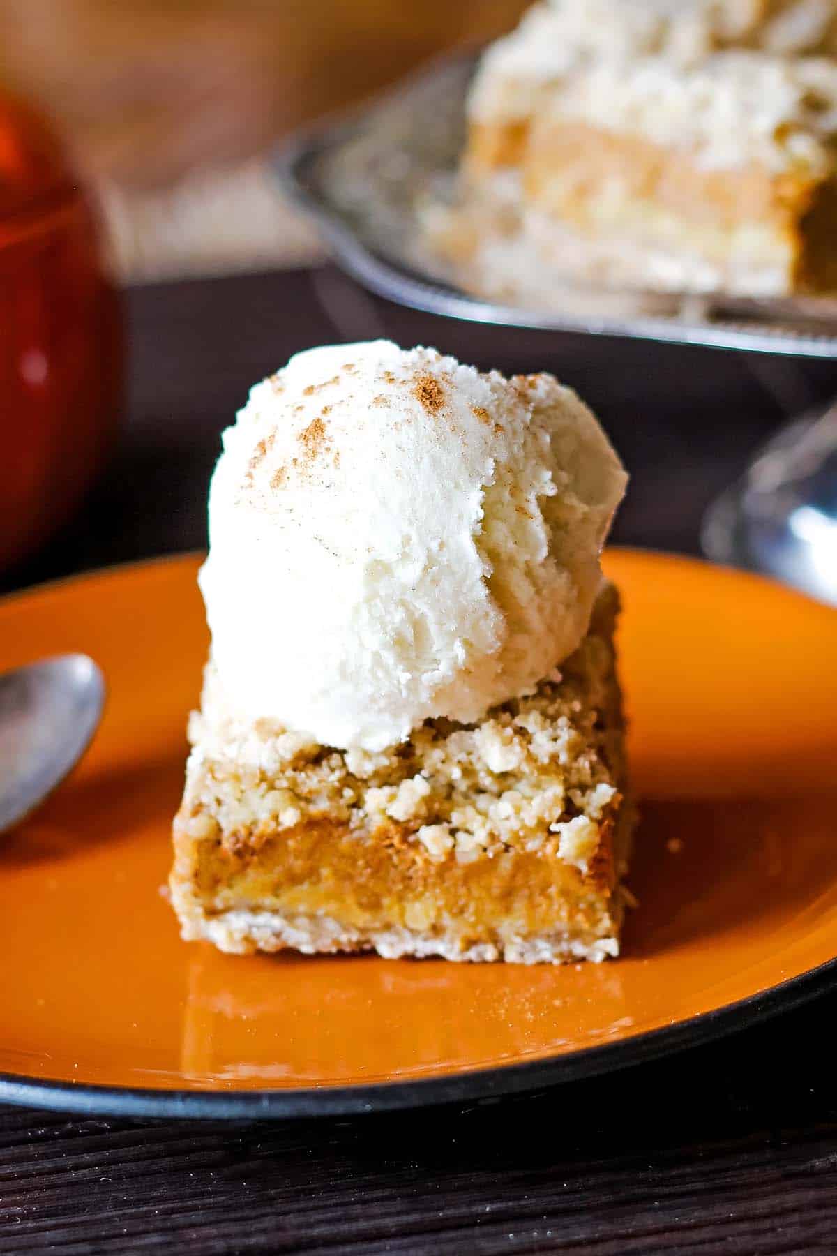 pumpkin bar with crust topped with vanilla ice cream scoop