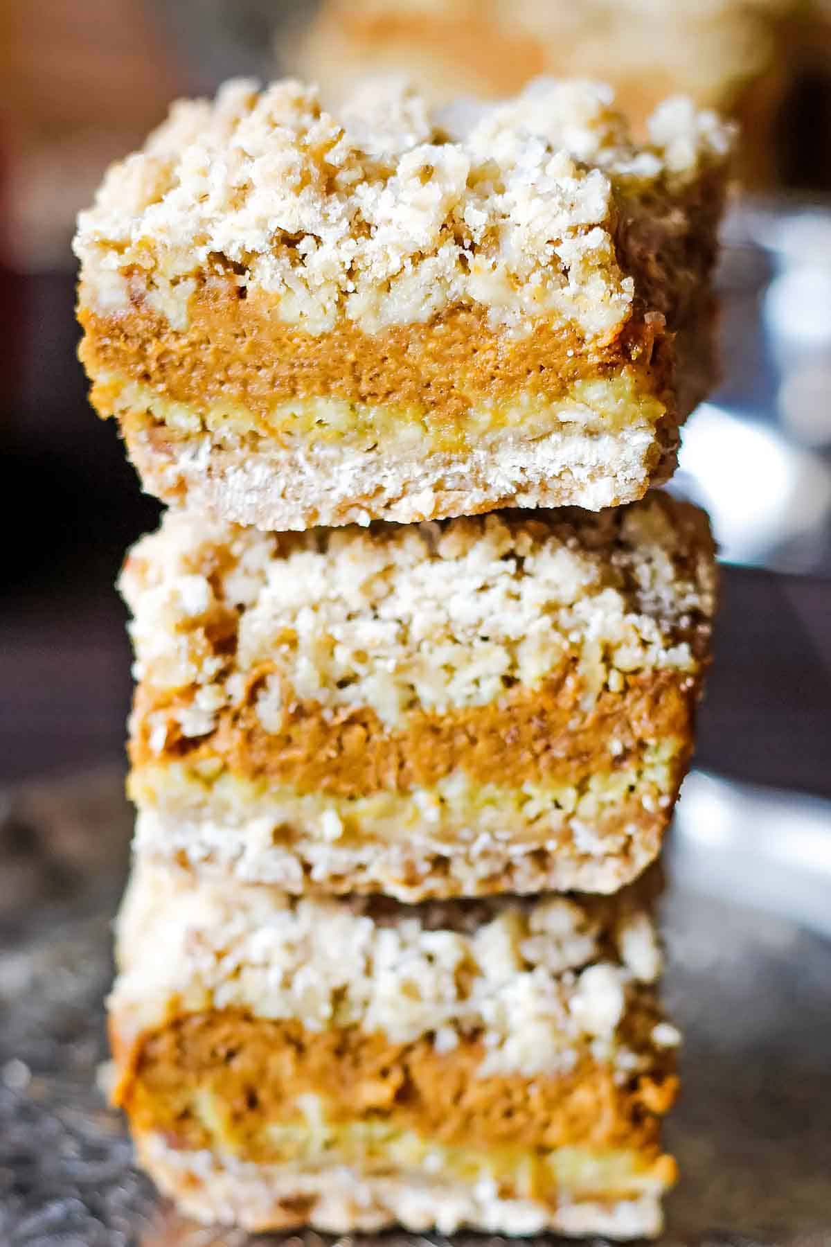 stack of 3 pumpkin dessert bars with cookie crust and crumb topping