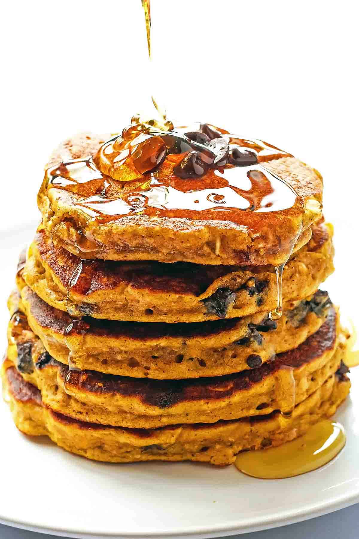 pumpkin oatmeal pancake stack with chocolate chip topping and syrup drizzle