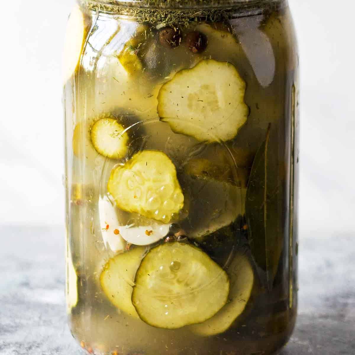 fermented cucumbers sliced in mason jar with cloudy brine and garlic and pickling spices