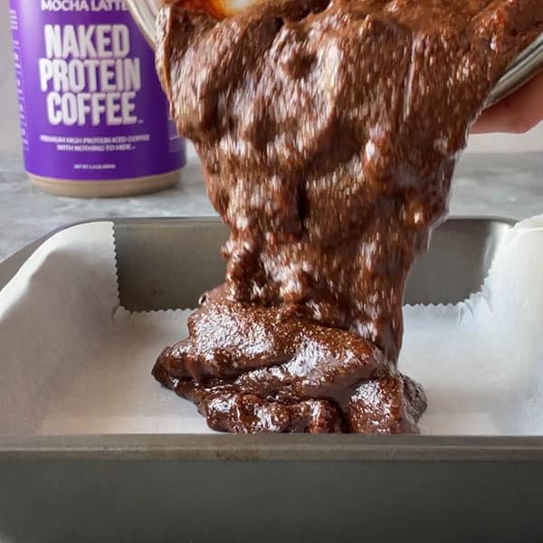 protein brownie batter pouring into lined pan