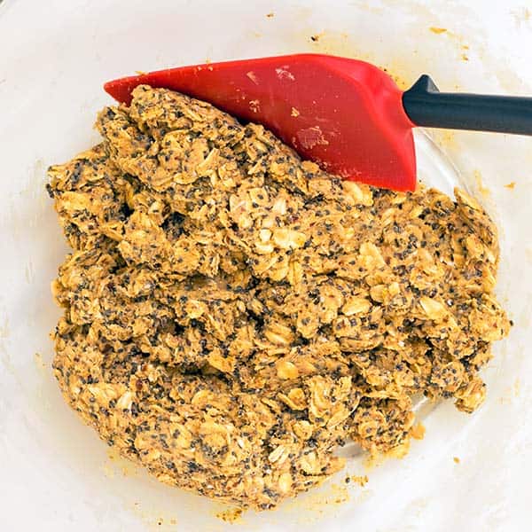 mixed up energy bites ingredients in bowl with red spatula
