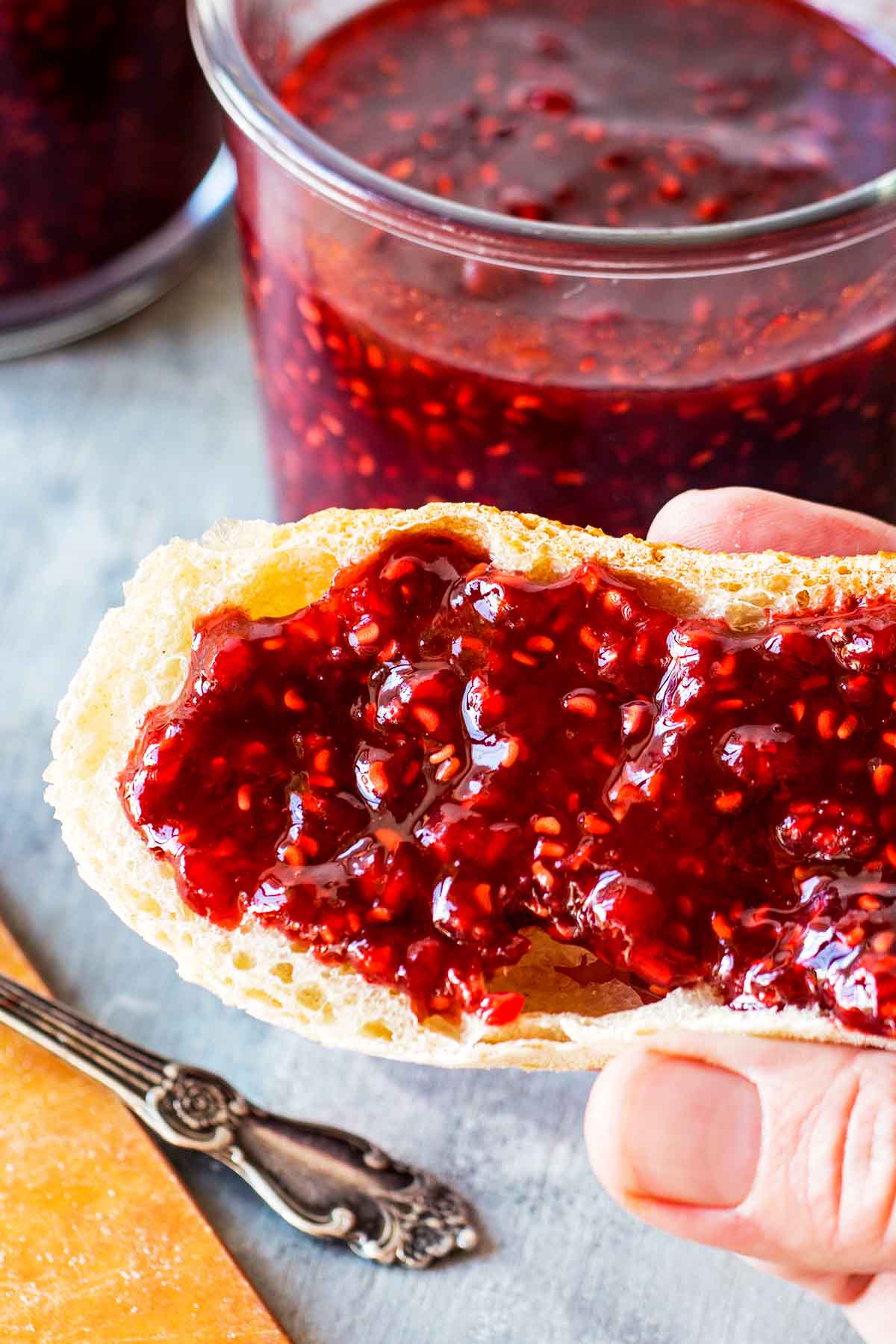 hand holding bread slice with raspberry spread