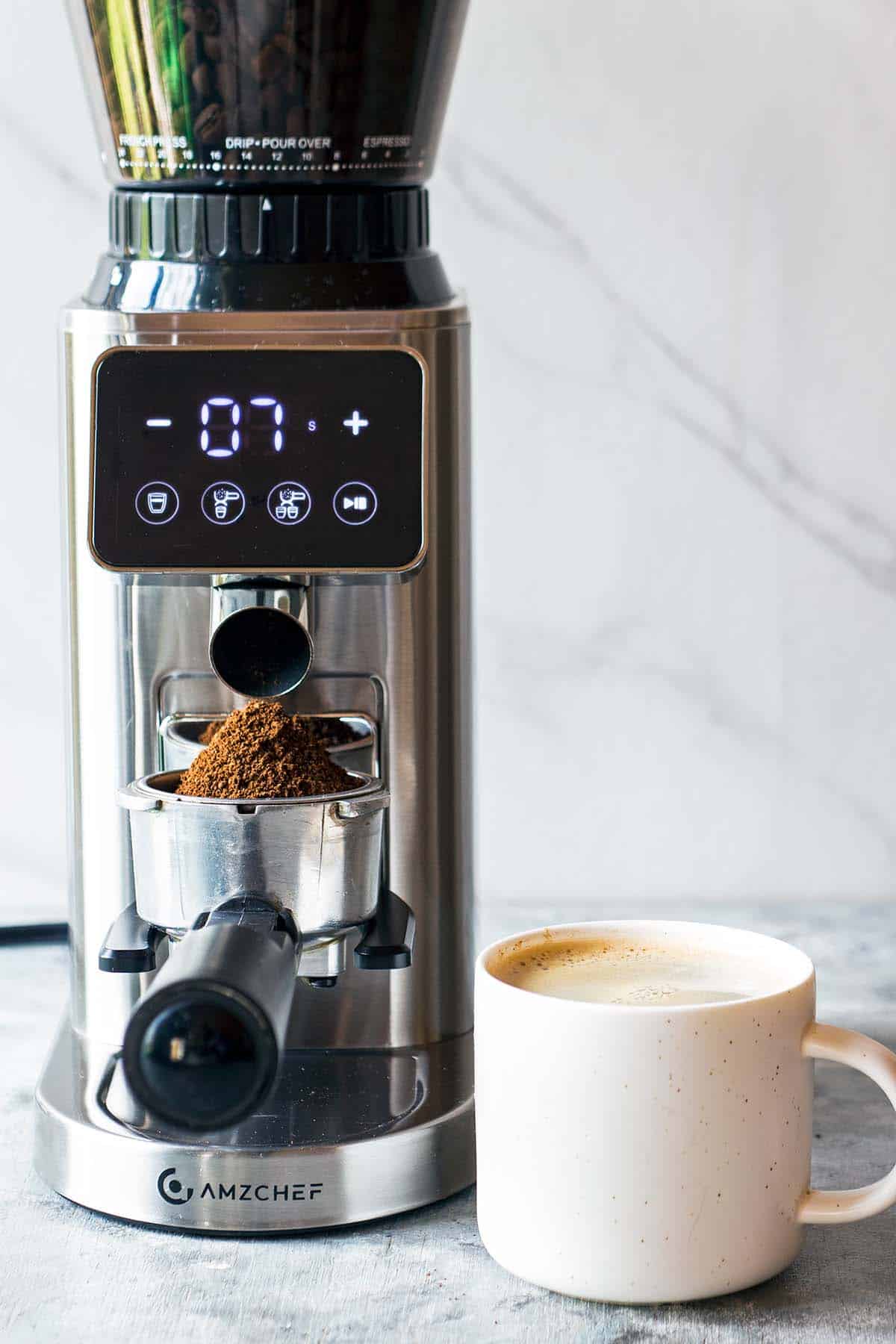 espresso coffee grinder with coffee cup next to it